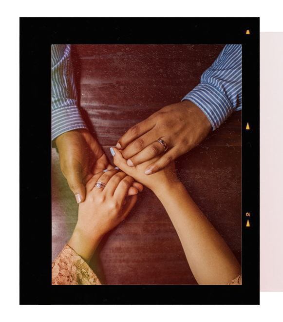 Two hands gently holding each other in warm golden light