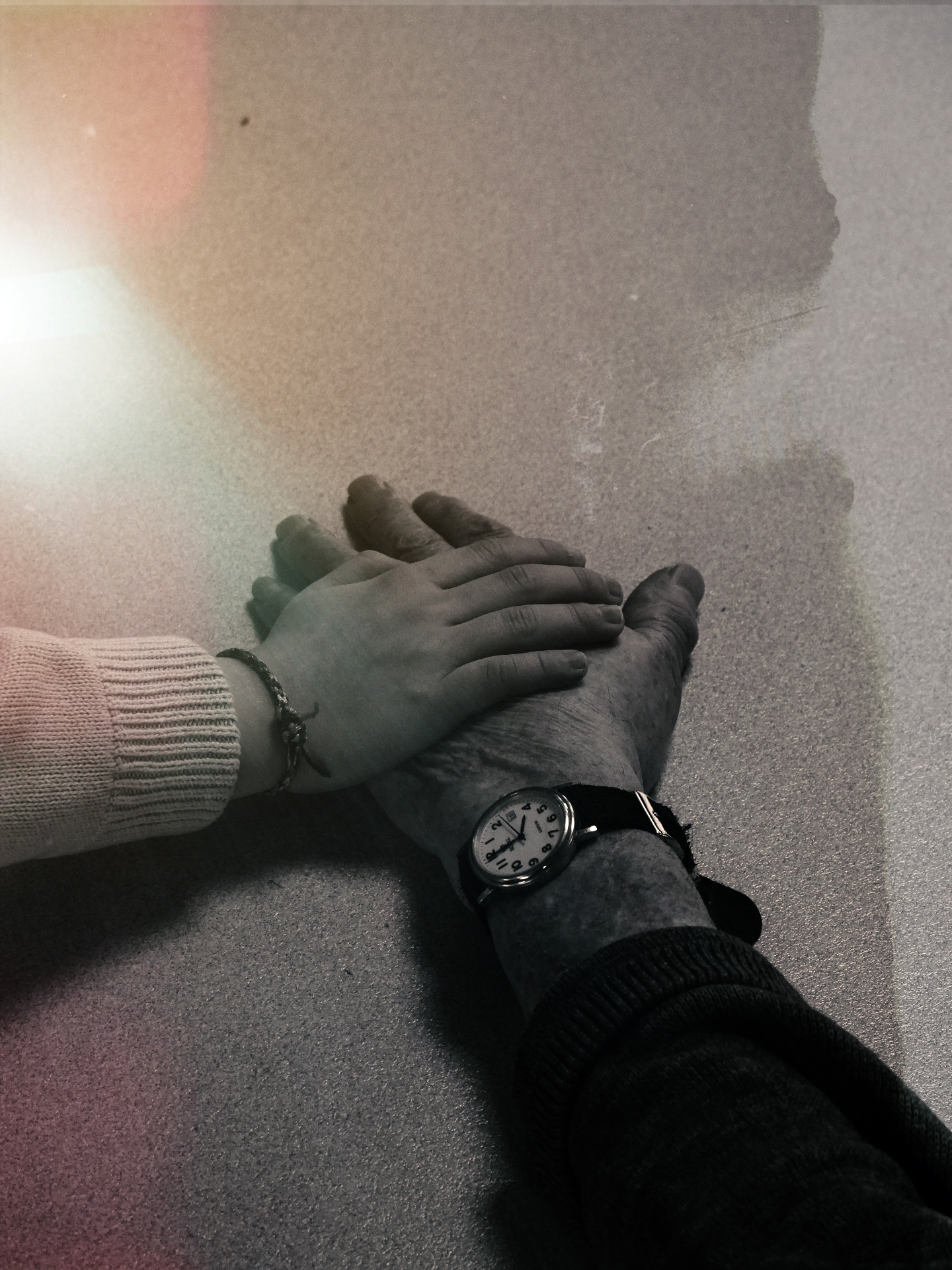 A younger hand resting gently on an older hand, a quiet act of staying close